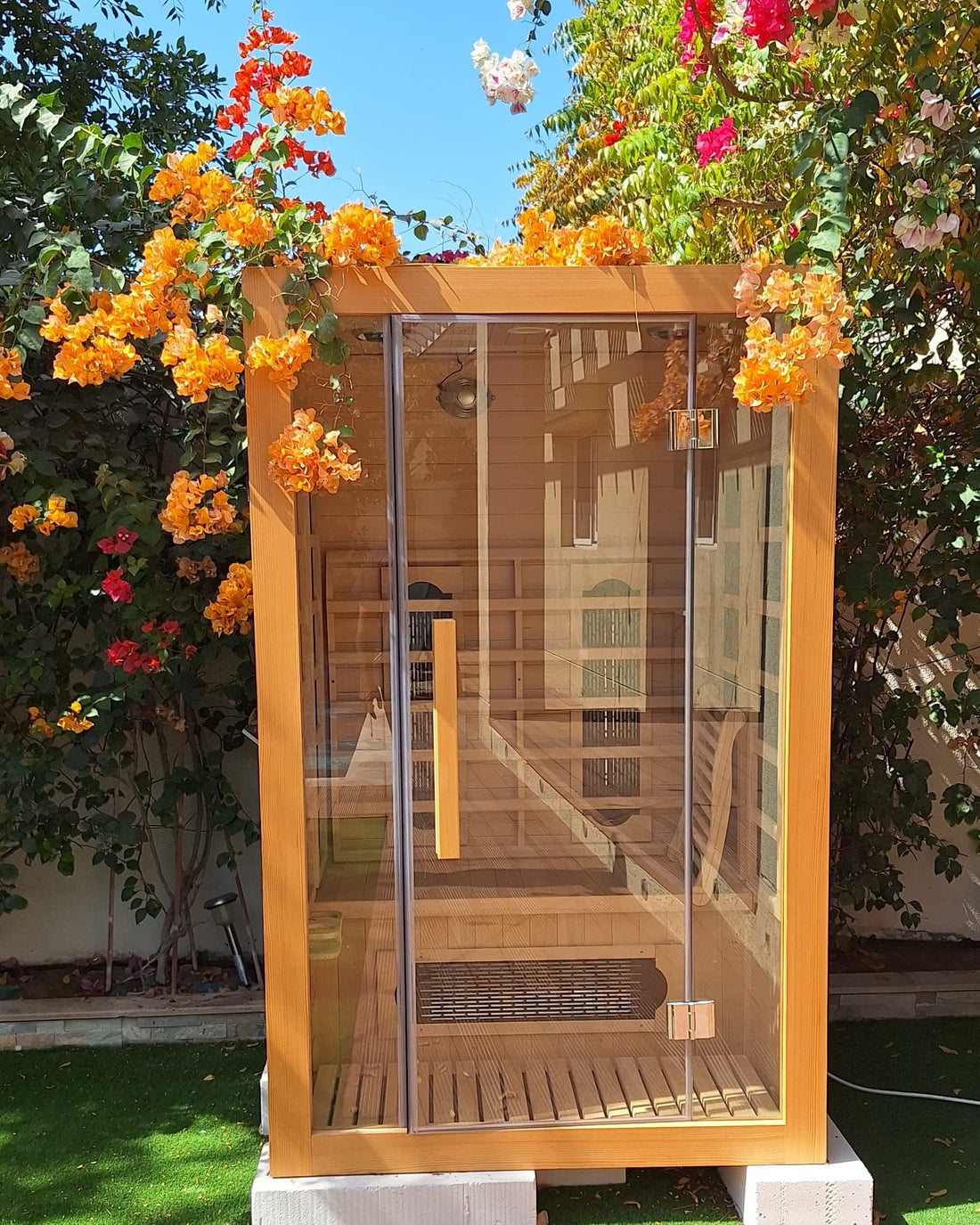 Two person infrared sauna cabin under bougainvillea in a Dubai villa garden