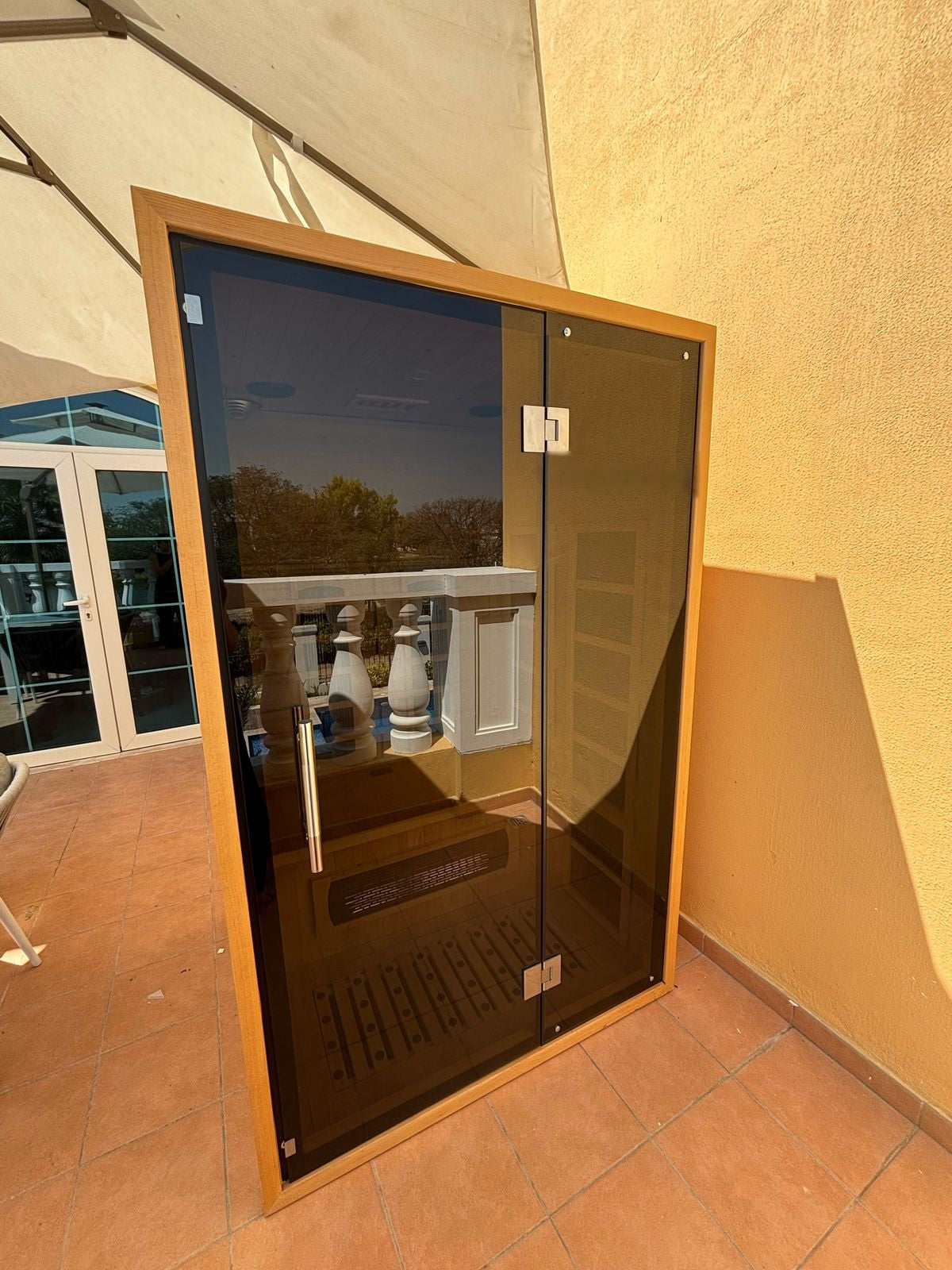 2 person full spectrum infrared sauna for sale in Dubai, Hemlock cabin with tempered glass front, installed on a covered terrace